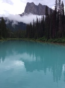 blue lake with clouds and forest in background